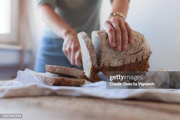 slicing freshly baked bread, close-up - woman bread stock pictures, royalty-free photos & images