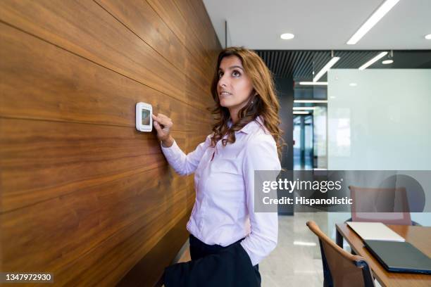 donna d'affari che accende il termostato in ufficio - termostato foto e immagini stock