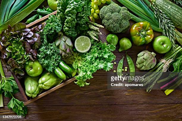 tischansicht hintergrund einer variation grünes gemüse für entgiftung und alkalische diät. in einer kiste auf einem rustikalen holztisch - leaf vegetable stock-fotos und bilder