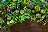 Table top view background of a variation green vegetables for detox and alkaline diet. Set in a crate on a wooden rustic table