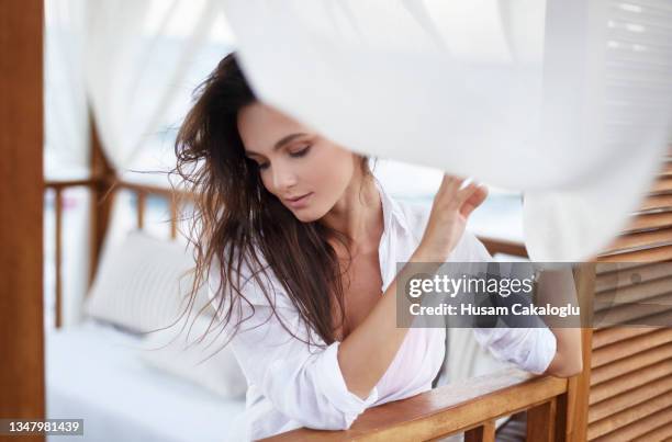 young woman behind the white curtain feeling the wind on the beach. - beautiful women stockfoto's en -beelden