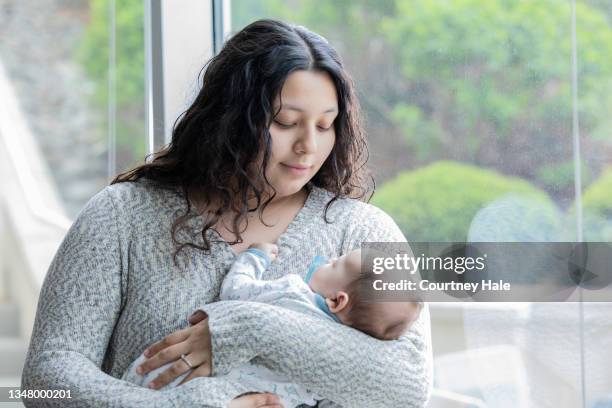 young mom holding newborn - tienerzwangerschap stockfoto's en -beelden