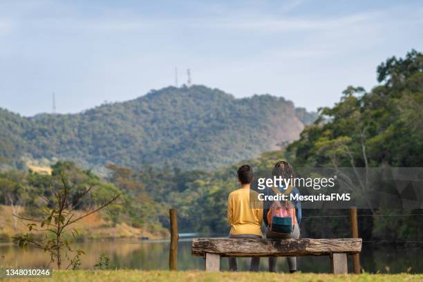 rear view of children sitting in front of the lake - moving down to seated position stock pictures, royalty-free photos & images
