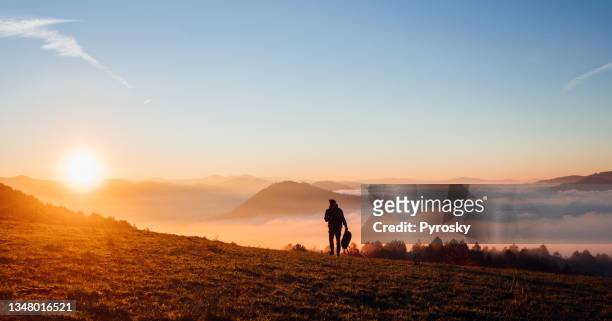 man standing on a hill above the cloudy valley at sunrise - horizon over land imagens e fotografias de stock