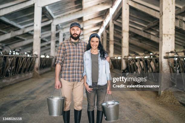 portrait d’une famille agricole confiante et prospère engagée dans l’élevage de vaches posant dans une étable - couple farm photos et images de collection