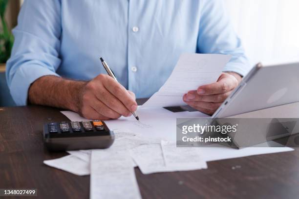 man calculating personal expenses at home - calculator tax forms stockfoto's en -beelden