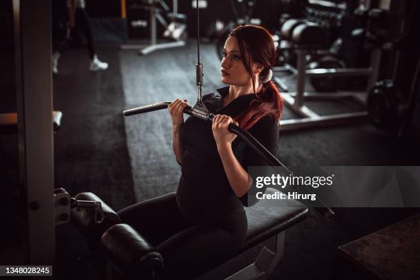 fit woman training on exercise machine - women's weightlifting stock pictures, royalty-free photos & images