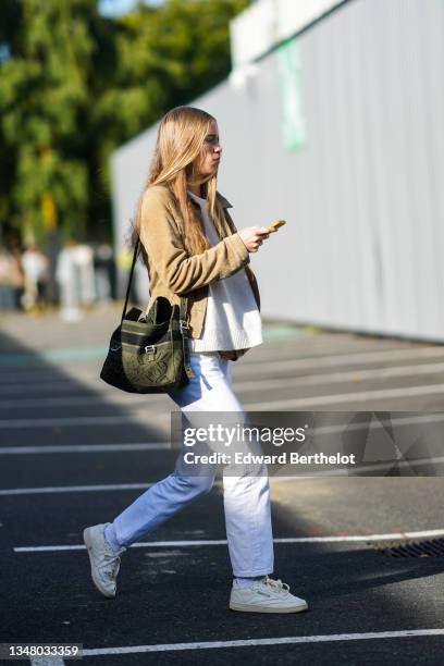 Guest wears a beige brown suede jacket, a white ribbed t-shirt, a khaki with black pattern fabric shoulder bag from Christian Dior, white denim...