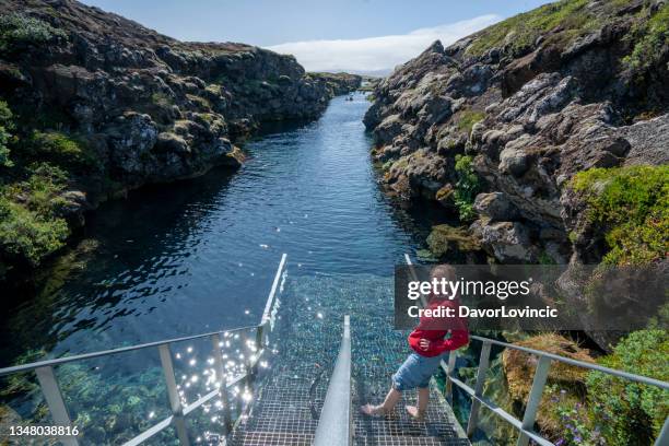 tourist woman in thingvellir national park at snorkeling entrance of silfra, iceland - thingvellir stock pictures, royalty-free photos & images