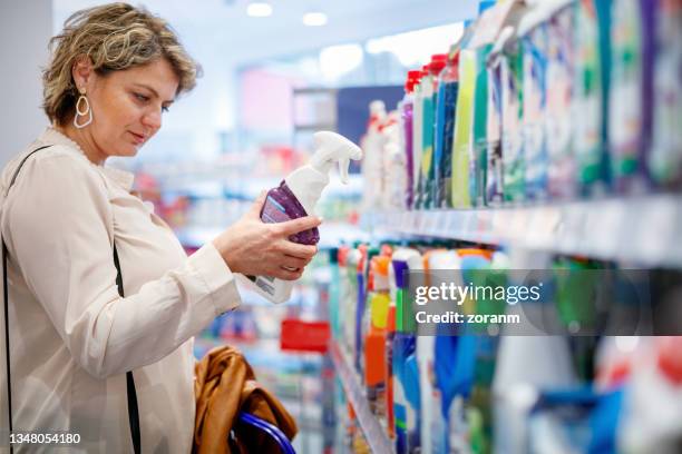 woman choosing domestic cleaning product by the supermarket shelf - cabide objeto manufaturado imagens e fotografias de stock