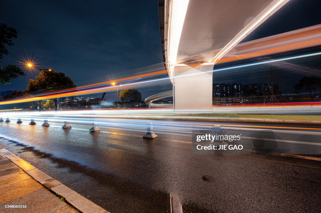 On a rainy night, a fast-moving vehicle beam was photographed under the modern overpass in Chengdu