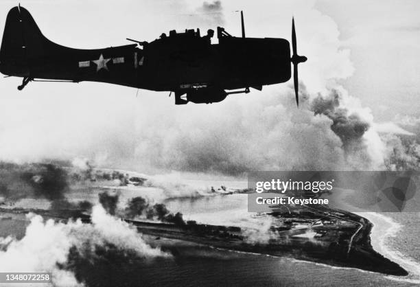 Silhouette view of a United States Navy Douglas SBD-5 Dauntless dive bomber of Bombing Squadron 5 from the aircraft carrier USS Yorktown flying over...