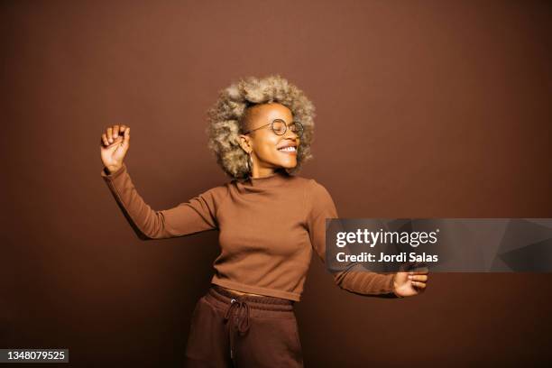 woman dancing against a brown background - afro woman fotografías e imágenes de stock