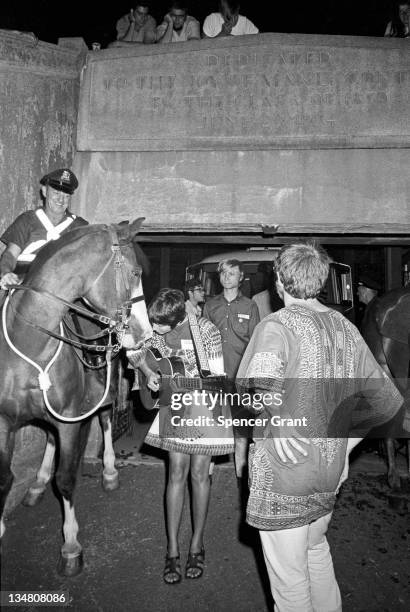 Pregnant Joan Baez serenades a cop's horse at Harvard Stadium, Brighton, Boston, Massachusetts, 1969.