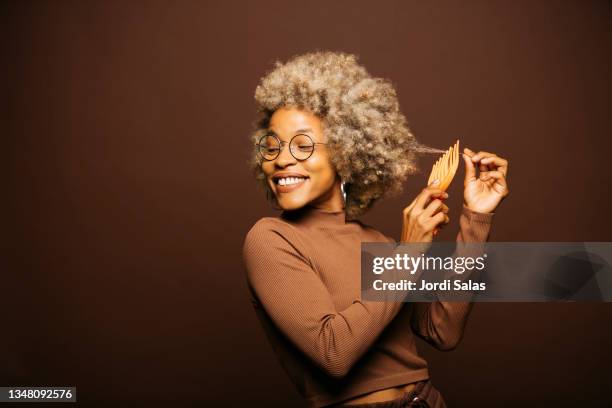 woman combing her afro hairstyle - hair brush stock pictures, royalty-free photos & images