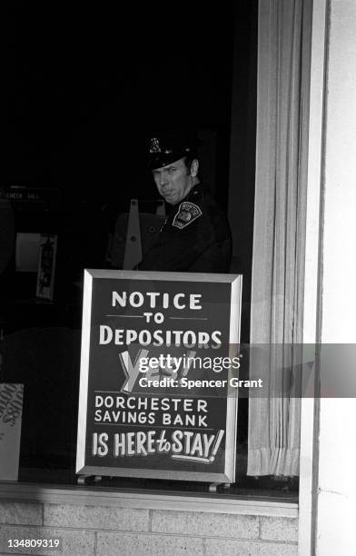 Determined bank sign and guard at Columbia Point, Dorchester, Boston, Massachusetts, 1970.
