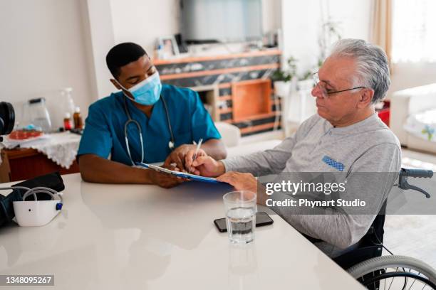 health visitor and senior man during home visit - förlamning bildbanksfoton och bilder