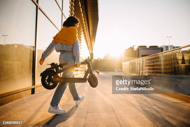 la donna porta il suo scooter elettrico - motor scooter foto e immagini stock