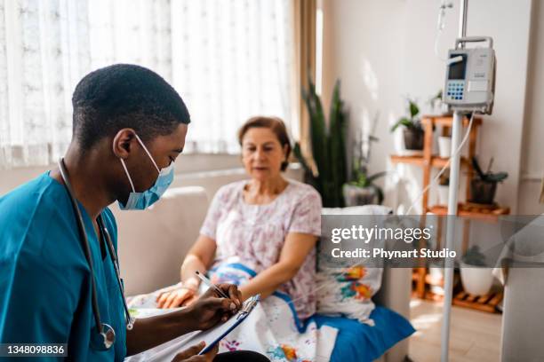 gesundheitsbesucherin und seniorin während des hausbesuchs - medizinisches gerät stock-fotos und bilder