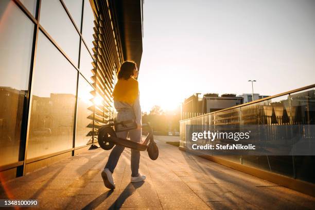 woman carries her electric scooter - electric push scooter stock pictures, royalty-free photos & images