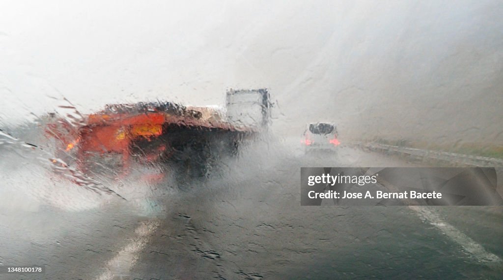 Car point of view driving, truck passing on a wet highway with lots of rain.