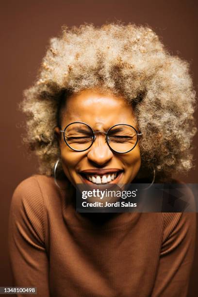 portrait of a woman against a brown background - frau gesicht brille stock-fotos und bilder