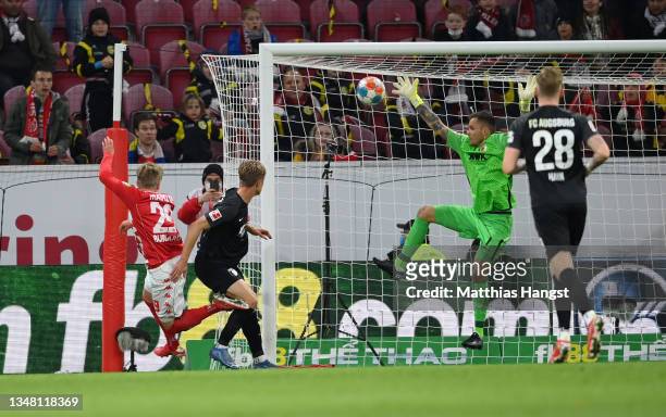 Jonathan Burkardt of 1.FSV Mainz 05 scores their team's third goal under pressure from Robert Gumny of FC Augsburg during the Bundesliga match...