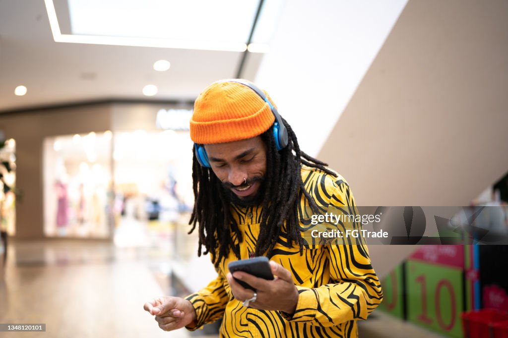 Mid adult man listening to music on the smartphone at the mall