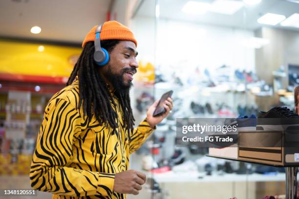 mid adult man listening to music on the smartphone at the mall - headphones in store stock pictures, royalty-free photos & images