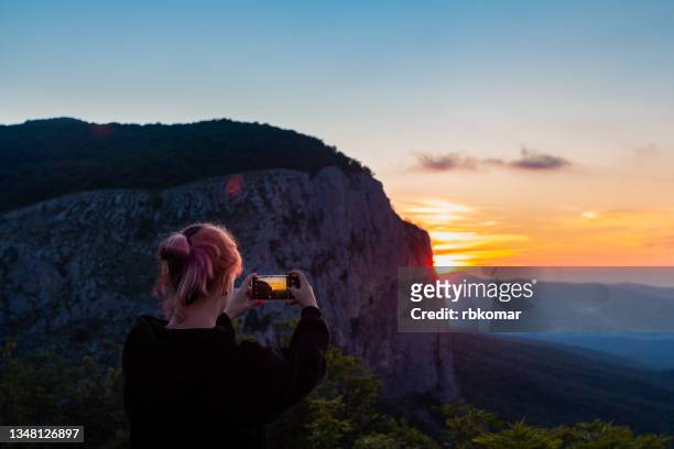 girl traveler enjoy the nature mountain peak by mobile phone device taking shot the the morning sunrise - russia travel stock pictures, royalty-free photos & images