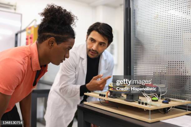 teacher teaching an african american student in a robotics class - stem topic stock pictures, royalty-free photos & images