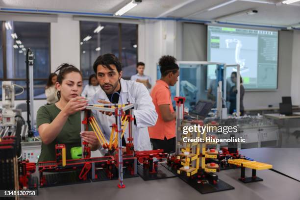 teacher helping a female student in a robotics class at the university - stem stock pictures, royalty-free photos & images