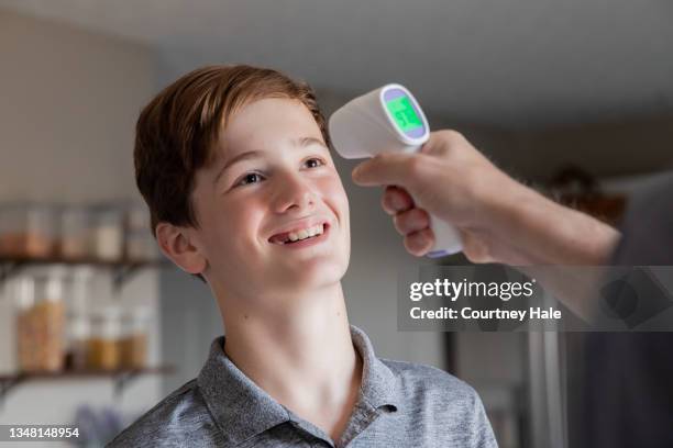 happy preteen boy gets temperature taking by infrared thermometer - infrared thermometer bildbanksfoton och bilder
