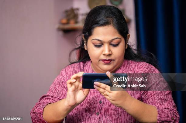 stylish indian girl using smartphone , watching movie or playing video game. - work video call stock pictures, royalty-free photos & images