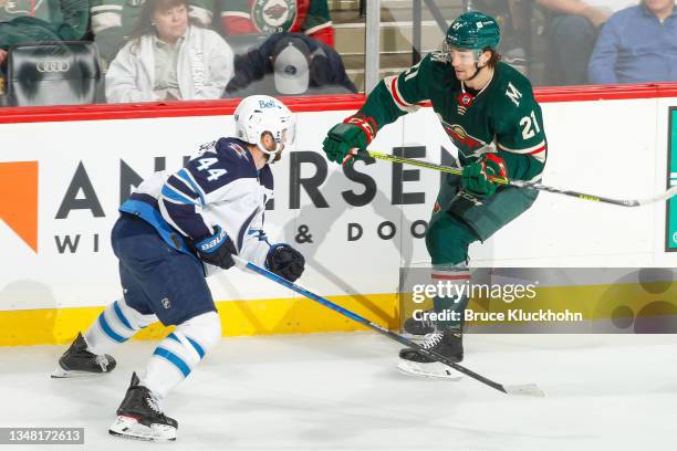 Josh Morrissey of the Winnipeg Jets defends Brandon Duhaime of the Minnesota Wild during the game at the Xcel Energy Center on October 19, 2021 in...