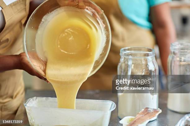 student pouring batter into baking dish during cooking class - forma de bolo imagens e fotografias de stock