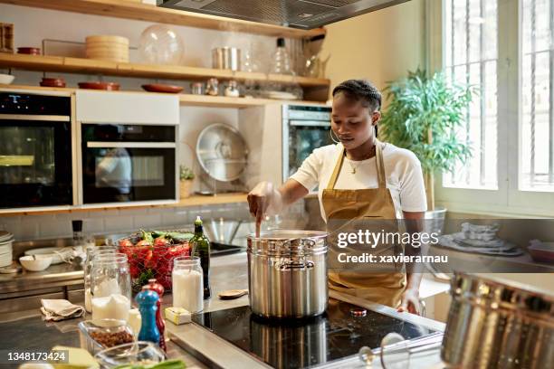 young african student stirring pot during cooking class - keramische plaat stockfoto's en -beelden