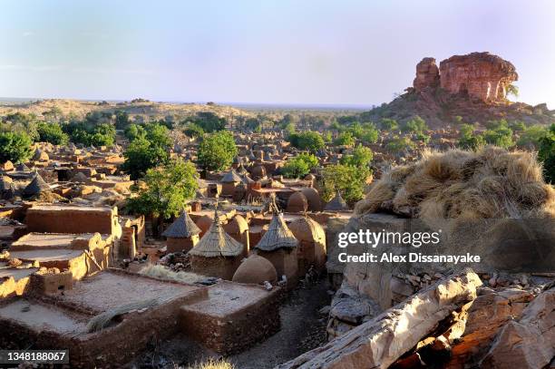 classic dogon country scenery, in banani village, with cone shaped granary towers, against rugged cliffs eroded by wind, seen  in mali, west africa - dogon stock pictures, royalty-free photos & images