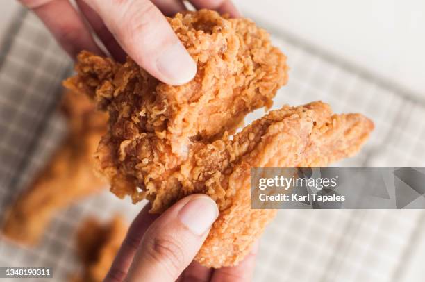 a southeast asian person holding fried chicken wings - knusprig stock-fotos und bilder