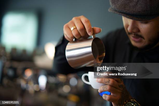 barista man pouring milk makes latte art - coffee art stockfoto's en -beelden