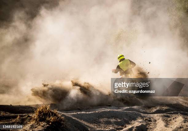 male motocross rider racing in dust, rear view - motocross stockfoto's en -beelden