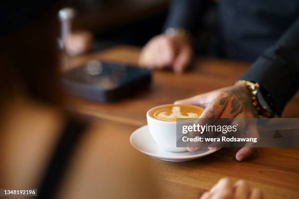 barista serving a cup of coffee latte to client - 盛り付け 手 ストックフォトと画像