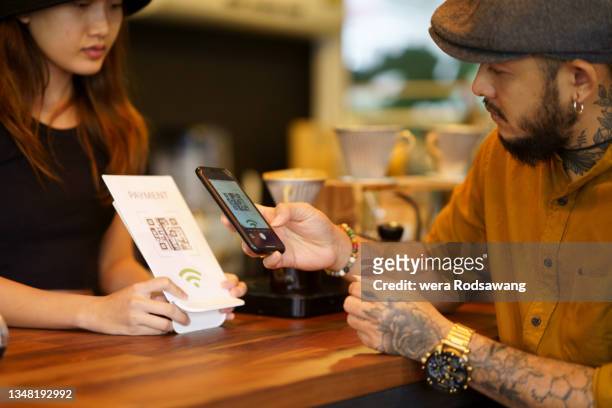 client using mobile scanning qr code payment in café - bar code imagens e fotografias de stock