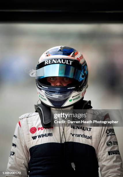 Looking at the camera, Finnish Williams Formula One team racing driver Valtteri Bottas walking along the pit lane while wearing his crash helmet,...