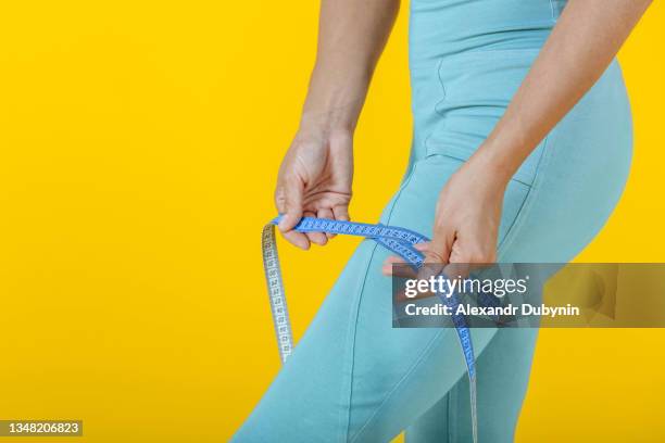 woman measures her leg with a hip tape. sport and diet concept - perfect female body shape fotografías e imágenes de stock