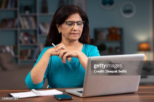 mature woman using laptop at home stock photo - financial planning seniors stock pictures, royalty-free photos & images