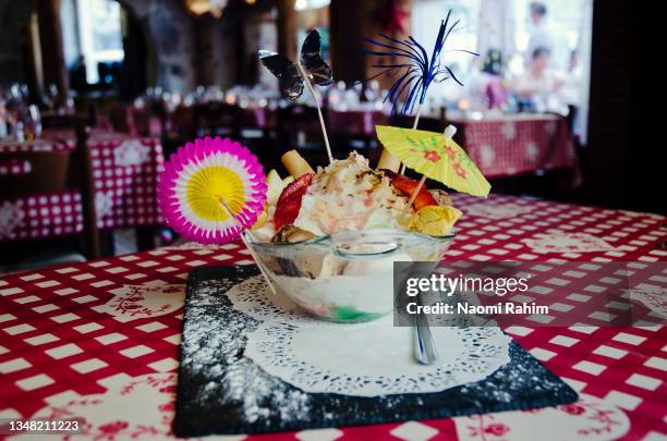 kids icecream sundae dessert, topped with small umbrellas and decorations - cocktail umbrella stock pictures, royalty-free photos & images