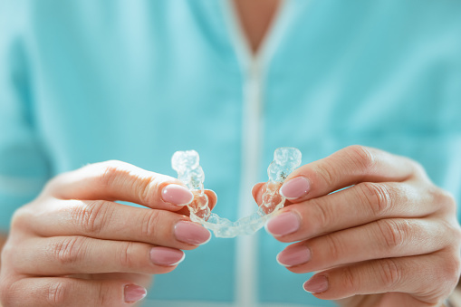 Woman holding transparent teeth aligner