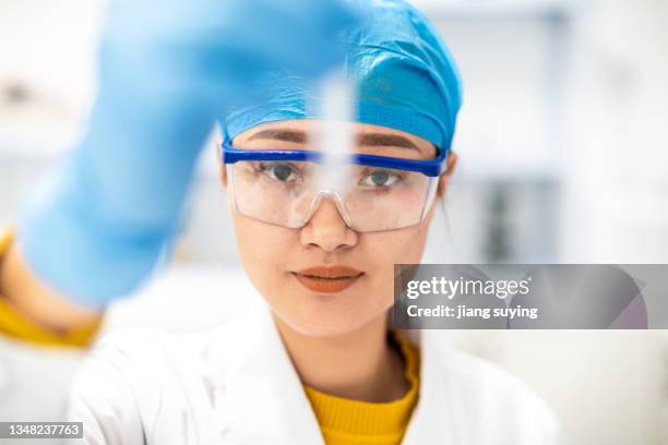 a young asian female scientist looks at reagents in the lab - clinical research stock pictures, royalty-free photos & images