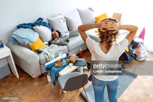 housewife at modern home on sunny day looking at dirty room. - drukte stockfoto's en -beelden
